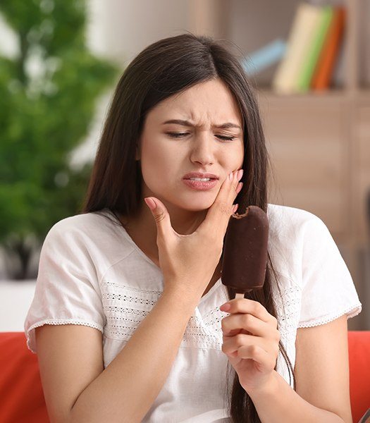woman holding jaw after biting ice cream
