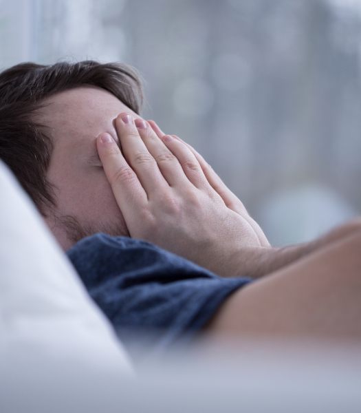 man covering face in bed