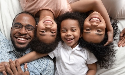 family of four laying in bed laughing