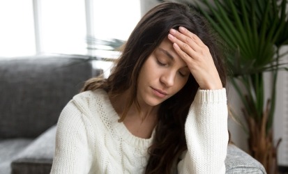 woman holding head and closing her eyes